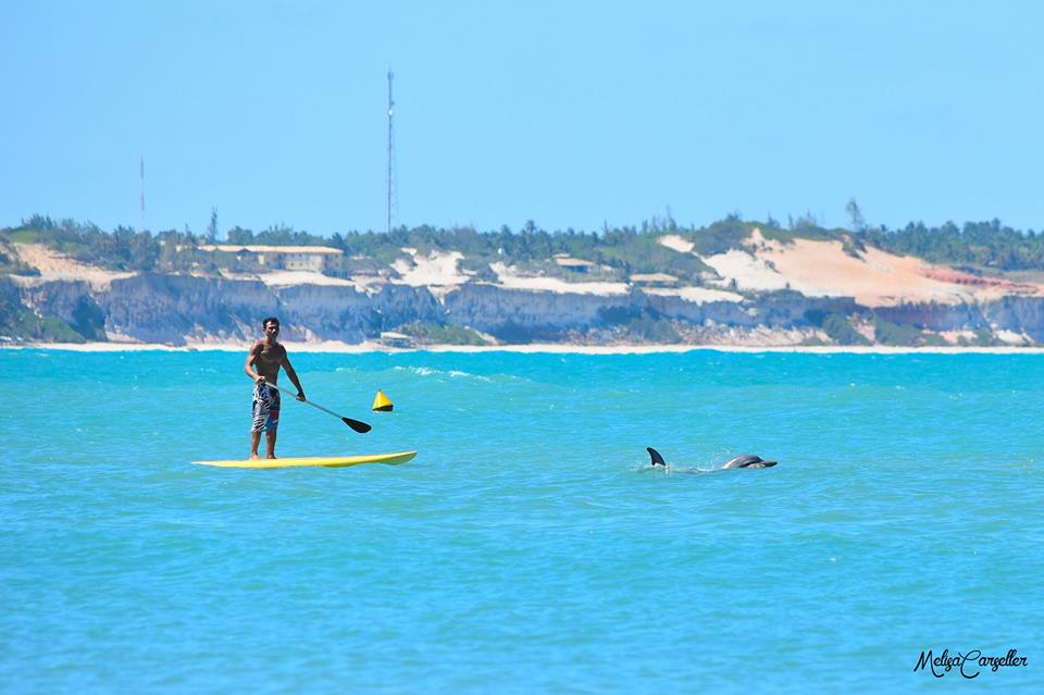Pessoa remando de stand up paddle no mar azul de Pipa